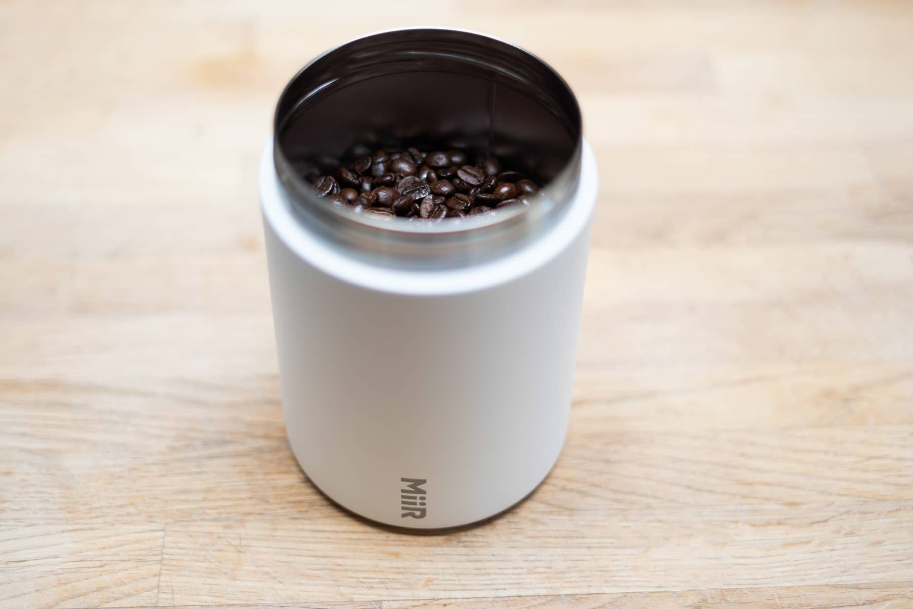 Coffee beans in an open white Miir coffee canister