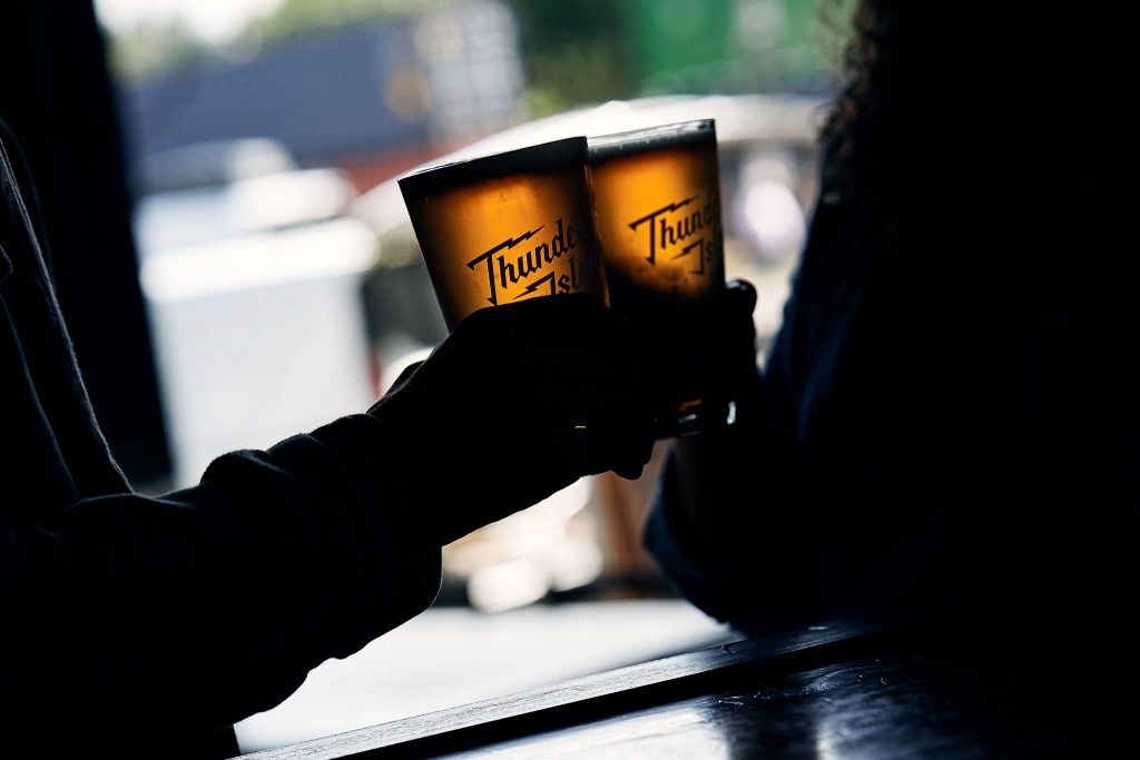 Cheers with two Thunder Island Brewing branded pint glasses