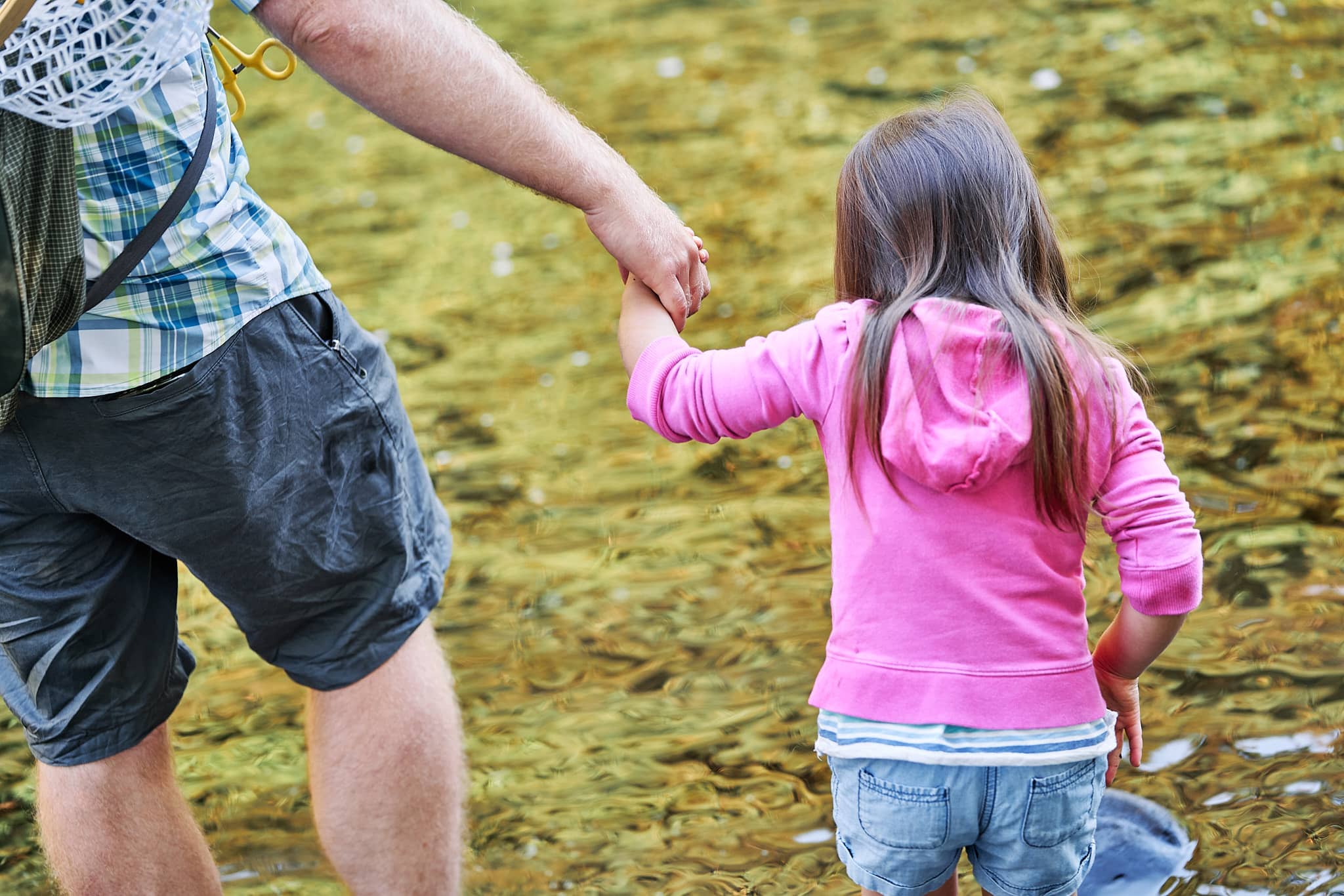 McKenzie and her Dad holding hands while walking through the river
