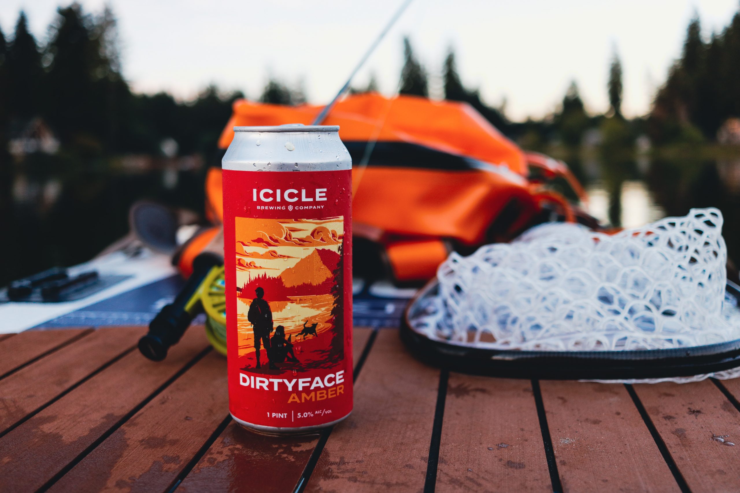 A can of Icicle Brewing's Dirtyface Amber Lager on a paddle board near fishing gear
