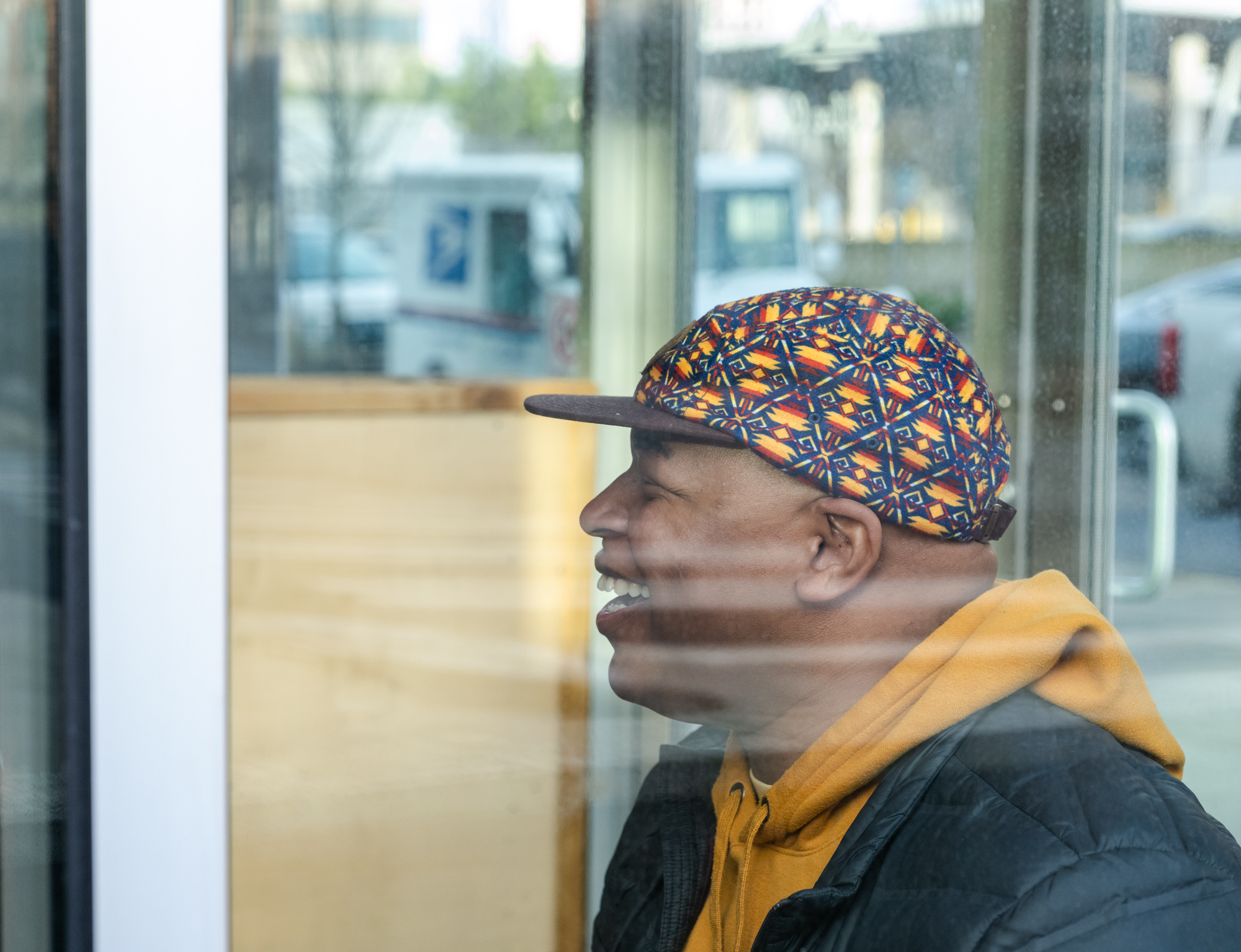 Quincy Henry laughing through the glass of Campfire Coffee