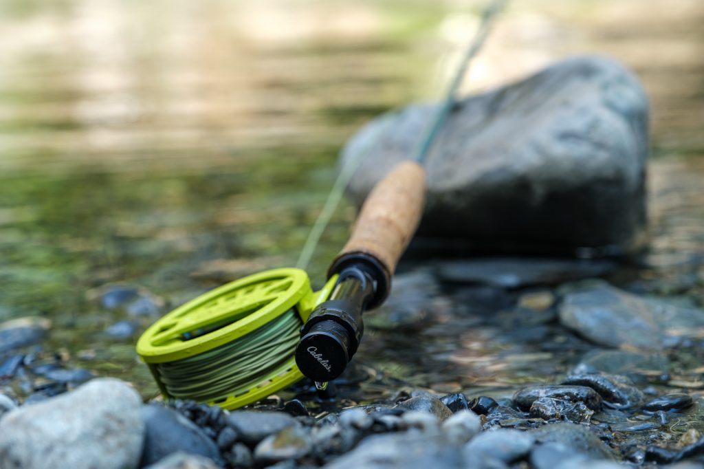A Cabelas fly rod laying in a shallow river