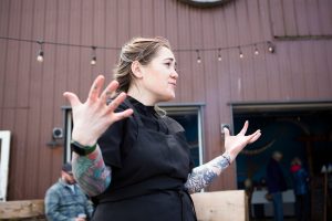 Executive Chef Sara Harvey standing in the courtyard of the Hook and Fork eatery wearing a black apron