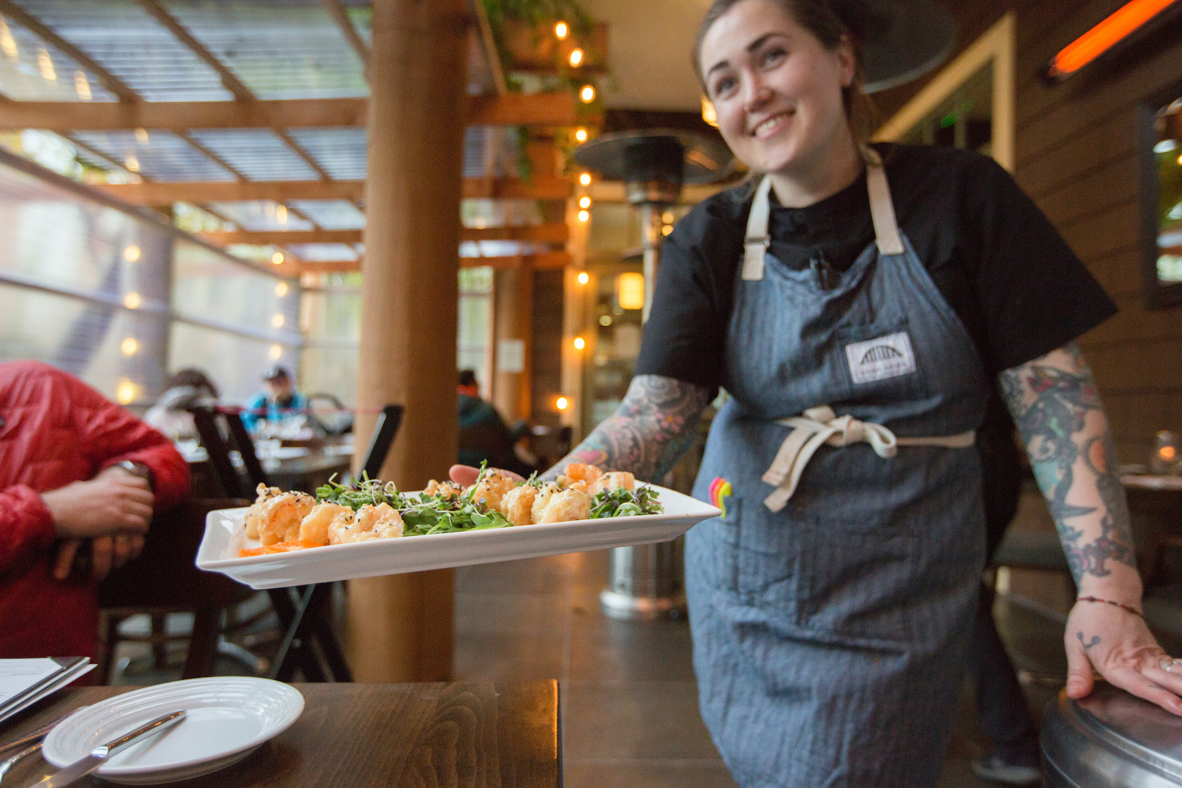 Alderbrook Resort & Spa's executive chef, Sara Harvey, delivering a plate of friend prawns and mixed greens to restaurant table