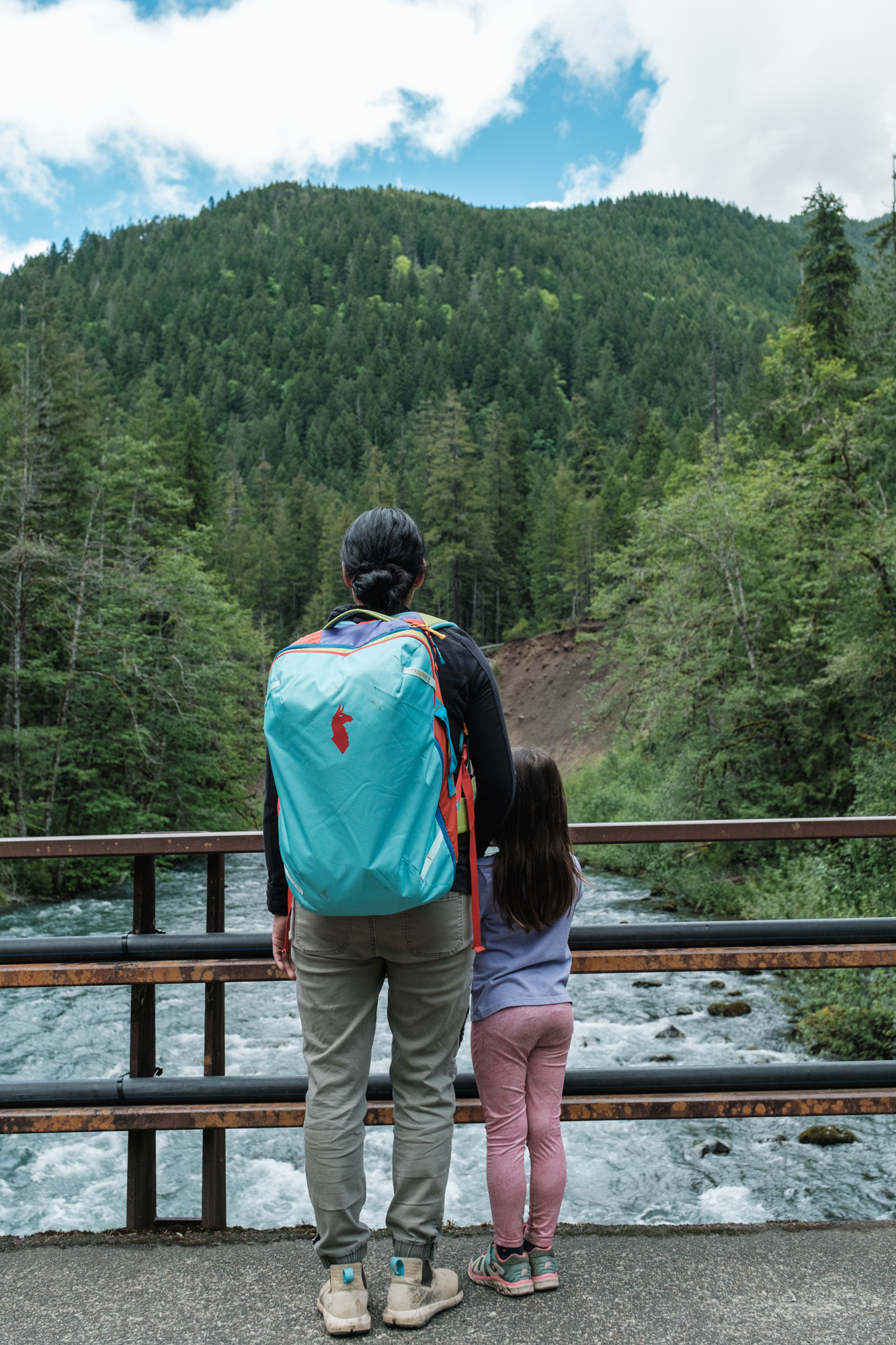 Mom and daughter looking over a river on a bridge