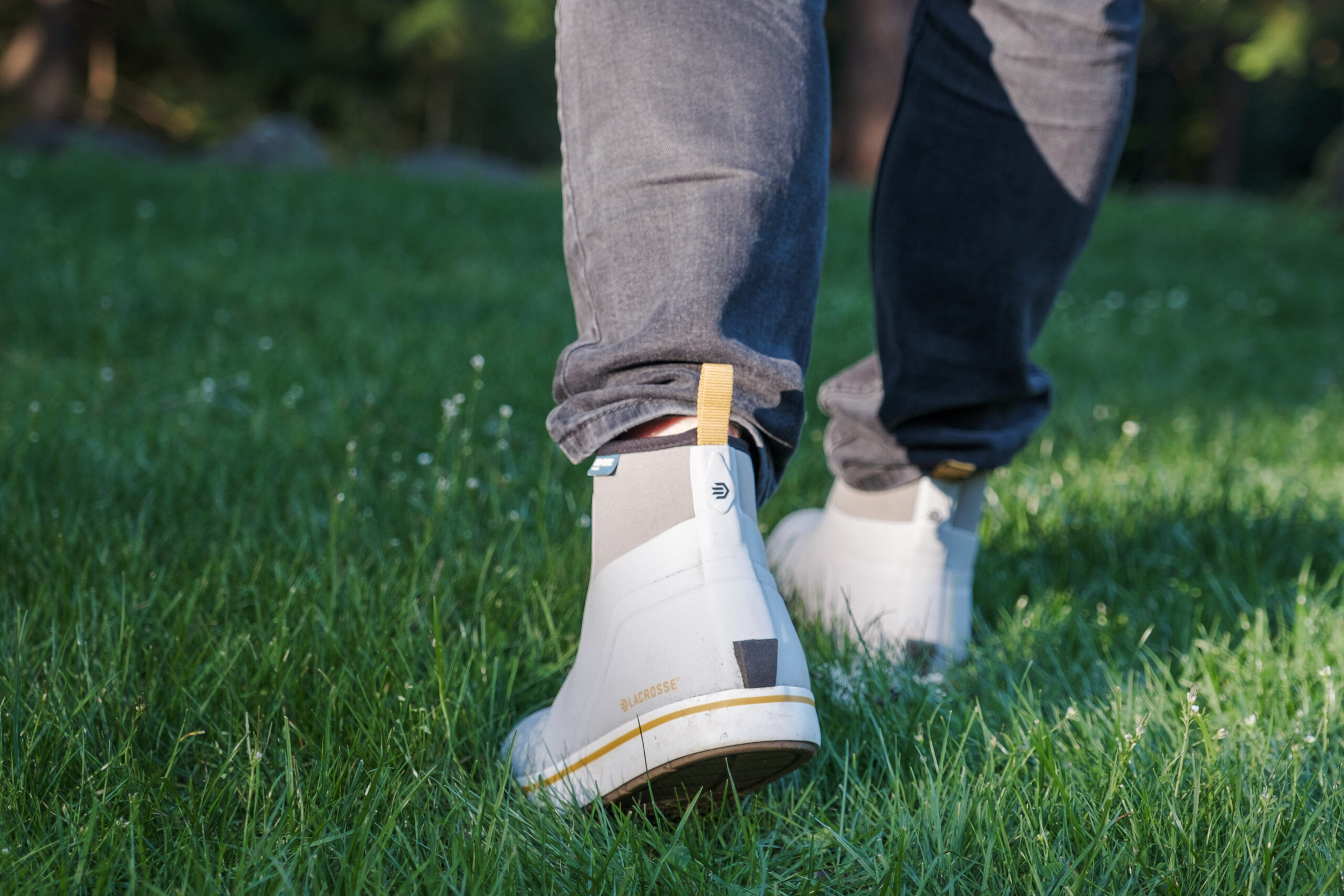 A man wearing LaCrosse boots walking through grass