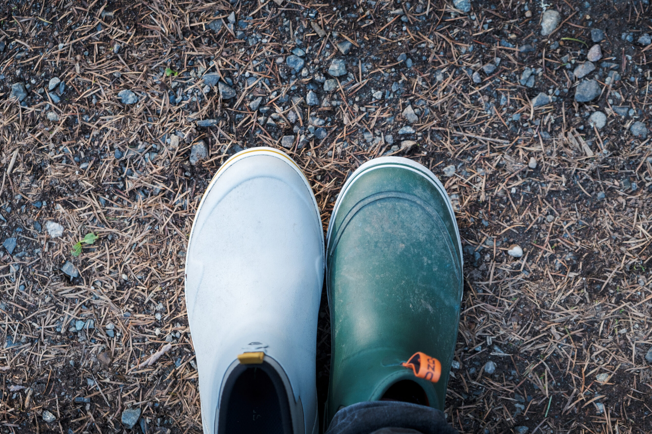 A light gray and a green rubber ankle boot next to each other viewed from above