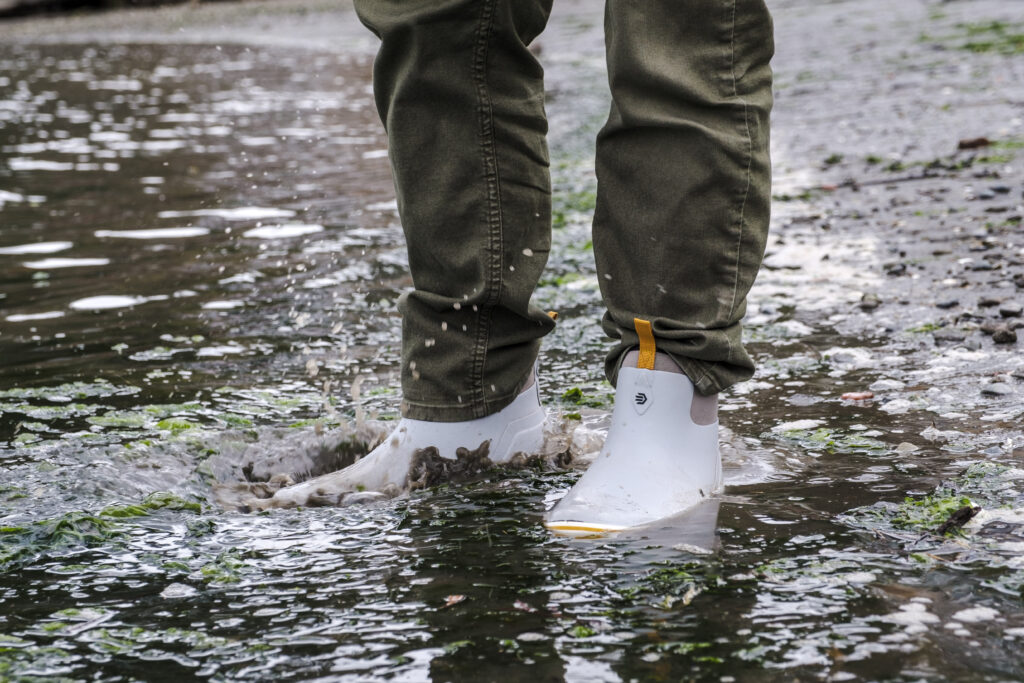 LaCrosse Alpha Deck Boots splashing in sandy water on a beach